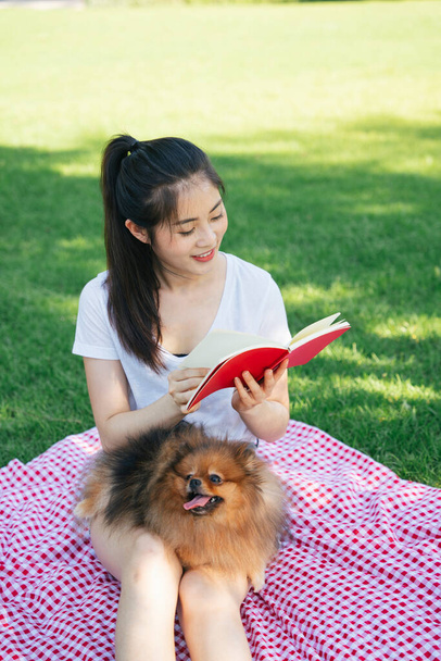 Propriétaire lisant un livre pour son chien au parc. Pique-niquer avec un adorable animal. - Photo, image