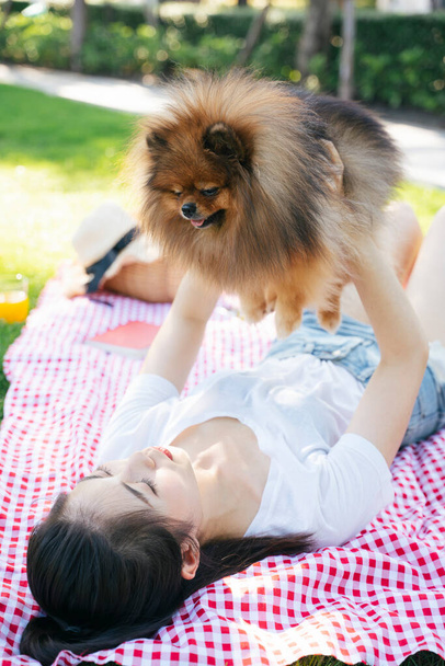 所有者は横になって公園で空気中の犬を持ち上げます.  - 写真・画像