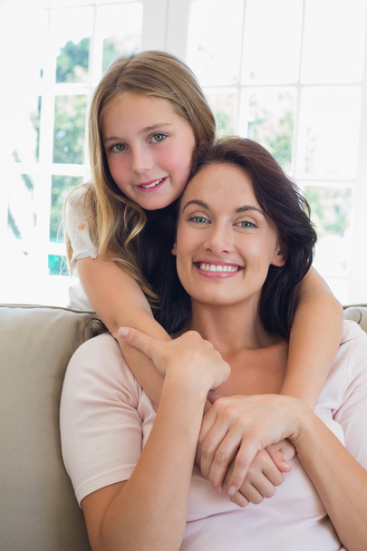 Girl embracing mother from behind at home - Foto, imagen