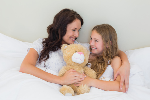 Mother and daughter with teddy bear in bed - Foto, imagen