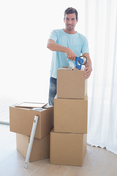 Young man with cardboard boxes in new house - Photo, image