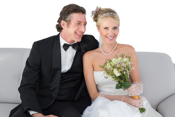 šťastné nevěsty sedí s ženichem na pohovce nad bílým pozadím - Fotografie, Obrázek