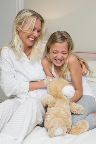 Mother tickling daughter in bed - Photo, image
