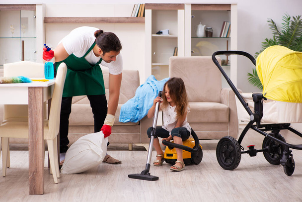 Junger männlicher Bauunternehmer putzt mit seiner kleinen Tochter das Haus - Foto, Bild