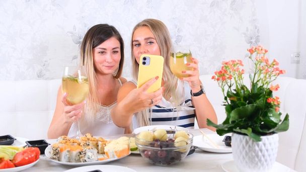 Δύο ευχαριστημένοι φίλοι μοιράζονται online περιεχόμενο χρησιμοποιώντας smartphone στο σπίτι, επιλεκτική εστίαση - Φωτογραφία, εικόνα