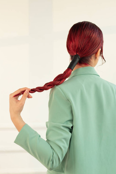 modelka ve stylovém obrazu drží ohon vlasů ve studiu s rukou - Fotografie, Obrázek