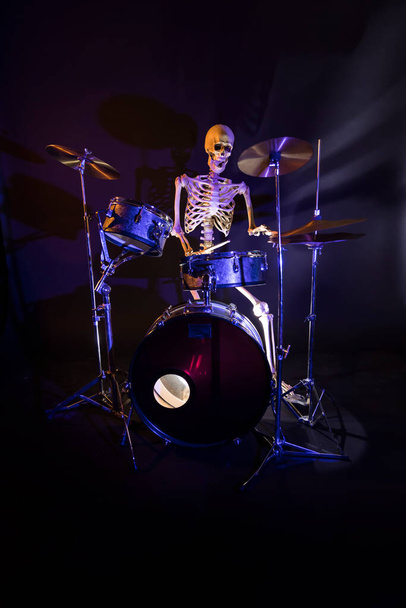 Білий скелет на темному фоні, що грає на наборі барабанів
 - Фото, зображення