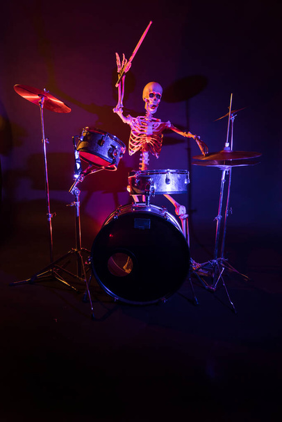 Skeleton playing a shiny drum lit by red lights - Photo, Image