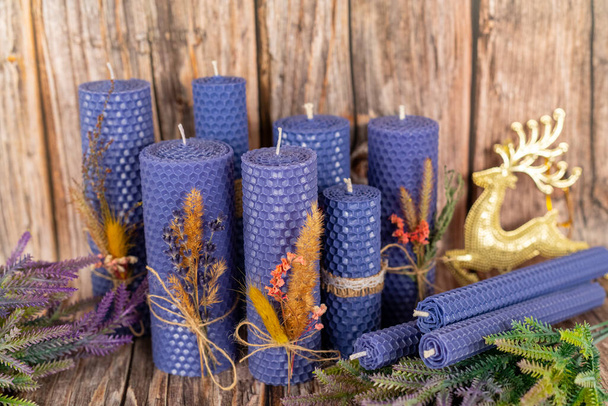 Lilac honing kaarsen handgemaakt van natuurlijke was op een achtergrond van houten planken. Elementen van natuurlijke materialen. Kerst of Nieuwjaarscompositie. Foto voor ansichtkaarten. - Foto, afbeelding