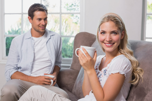 Relaxed couple with coffee cups sitting in living room - Φωτογραφία, εικόνα