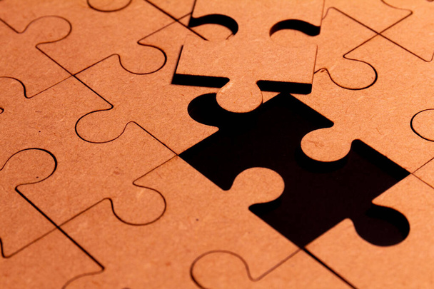 Vista ravvicinata di un puzzle marrone con un pezzo mancante - Foto, immagini