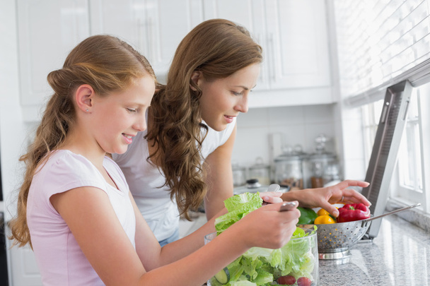 Girl helping mother to cut vegetables in kitchen - Photo, Image