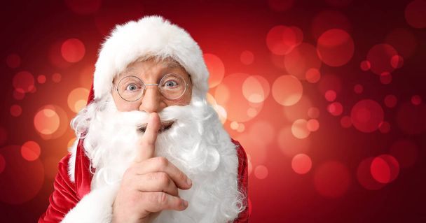 Портрет Санта-Клауса с жестом молчания на цветном фоне - Фото, изображение
