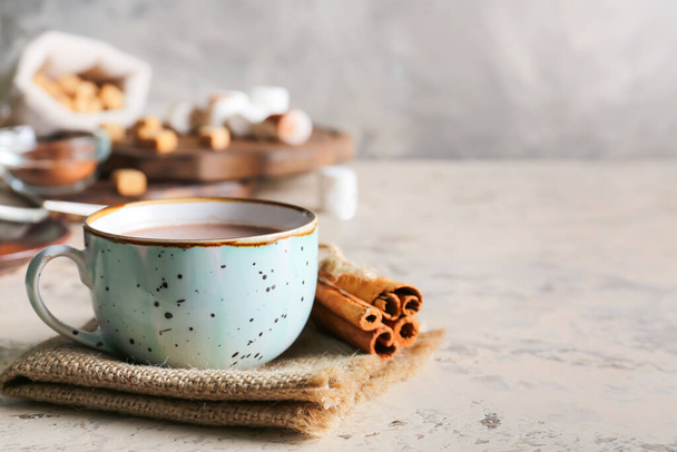 Cup of hot cacao drink with cinnamon on grey background - Photo, Image