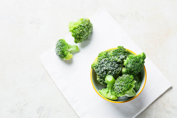 Bowl with frozen broccoli on light background - Foto, imagen