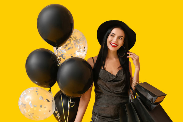 色の背景にショッピングバッグや風船と美しい若い女性。ブラック・フライデー販売 - 写真・画像