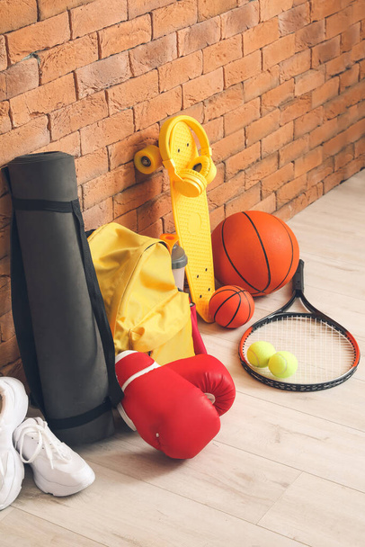 Комплект спортивного оборудования на полу возле кирпичной стены - Фото, изображение