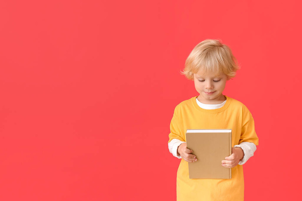 Χαριτωμένο μικρό αγόρι με το βιβλίο στο φόντο χρώμα - Φωτογραφία, εικόνα