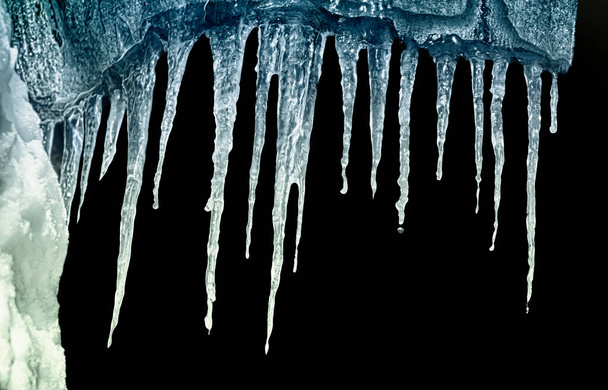 Reihe von Eiszapfen in einem Keller auf schwarzem Hintergrund isolieren Clipping - Foto, Bild
