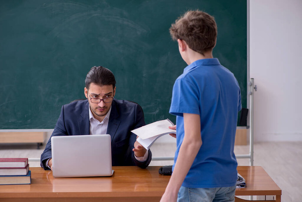 Fiatal férfi tanár és iskolás fiú az osztályteremben - Fotó, kép