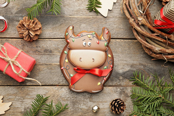 Νόστιμο μπισκότο σε σχήμα ταύρου και χριστουγεννιάτικη διακόσμηση σε ξύλινο φόντο - Φωτογραφία, εικόνα