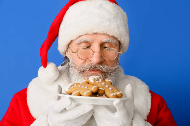 Άγιος Βασίλης με νόστιμα μπισκότα μελόψωμο στο φόντο χρώμα - Φωτογραφία, εικόνα