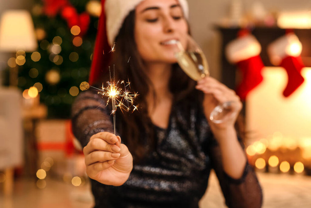 Jonge vrouw met kerstster en champagne thuis - Foto, afbeelding