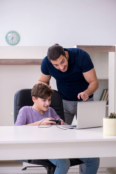 Mladý otec a školák hrají počítačové hry doma - Fotografie, Obrázek
