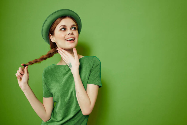 Happy woman with shamrock on St. Patricks Day in green clothes and a hat on her head gesturing with her hands - Фото, изображение