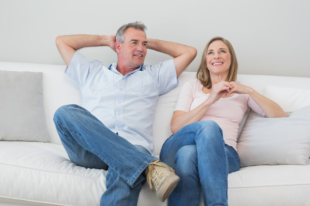 Happy relaxed couple sitting on sofa in living room - 写真・画像