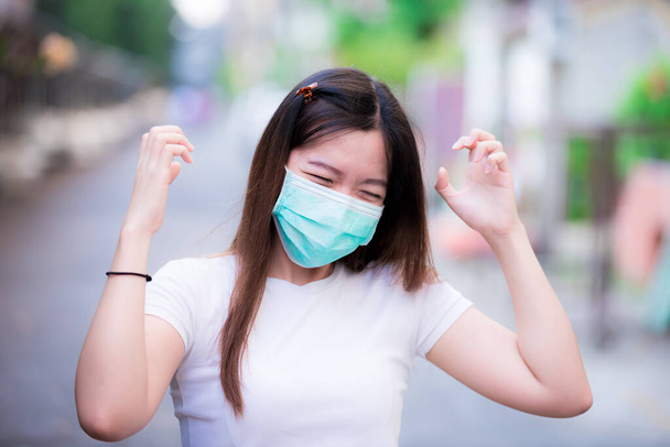 A zöld orvosi maszkot viselő ázsiai nők depressziósak a kialakulóban lévő koronavírus vagy COVID-19 új életmódbeli gyakorlata miatt. Beleértve a bérek csökkentésével járó stresszt is. Zavart női kifejezés. - Fotó, kép