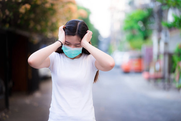 Ženy v masce zelené lékařské tváře vykazovaly úzkostné bolesti hlavy nebo stres, když propukla epidemie koronaviru. Osoba nosí masku na ochranu proti virům a malým částicím. - Fotografie, Obrázek