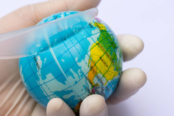 Concept of destroying the global environment from plastic steak knife. Hand of the people holding blue globe and using a plastic knife to cut the globe shows the destruction. Isolated white background - Photo, Image