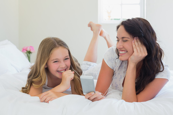 Mother and daughter listening to music in bed - Φωτογραφία, εικόνα