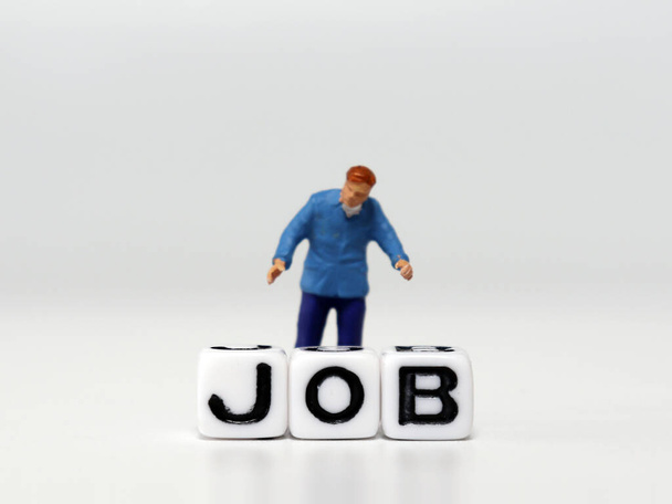 De miniatuurman die achter de JOB woordkubus staat. Het begrip banentekort. - Foto, afbeelding