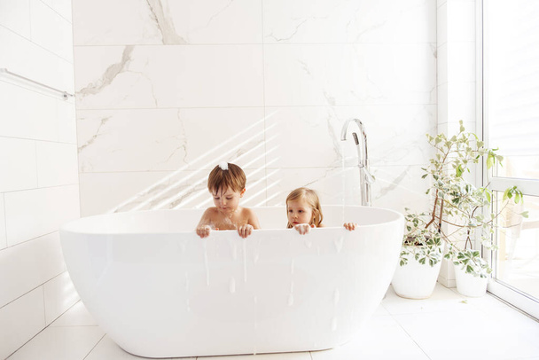 Little brother and sister having fun and taking a bubble bath - Valokuva, kuva