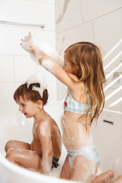 Little brother and sister having fun and taking a bubble bath - Foto, immagini