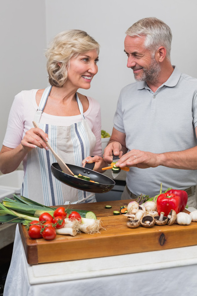 Mature couple preparing food together in kitchen - 写真・画像