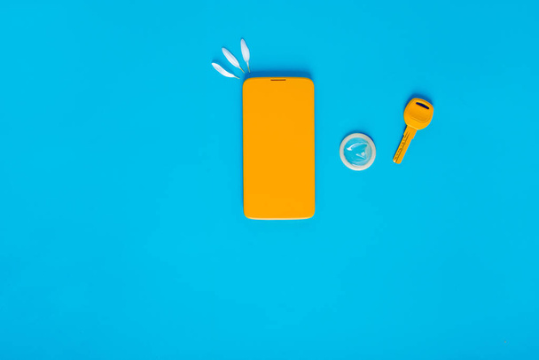 Tasainen lay koostumus kondomi, avain, puhelin sinisellä pohjalla. Eroottisia käsitteitä. Laadukas kuva - Valokuva, kuva