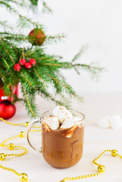 Hot chocolate with coconut milk and carob in a glass mug on the background of a Christmas tree. - Photo, Image
