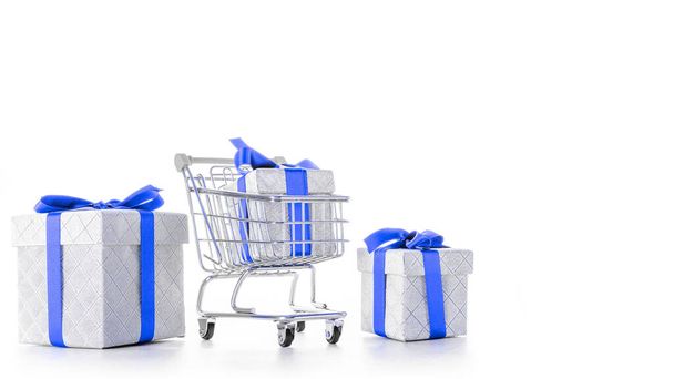 Gift box isolated. Trolley cart for supermarket with christmas or birthday gift box isolated on white background. Sale, discount, shopaholism concept. Consumer society trend - Foto, Bild