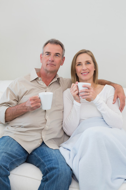Relaxed loving couple with coffee cups in living room - Foto, afbeelding