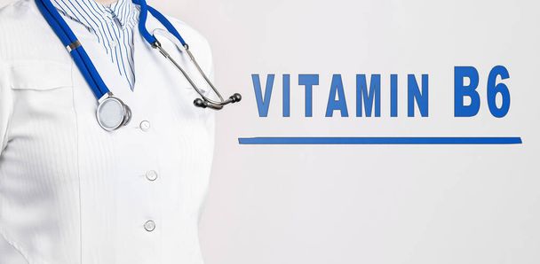 Word VITAMIN B6は白い背景にあります。近くには白いコートと聴診器の医者がいる。医学的概念 - 写真・画像