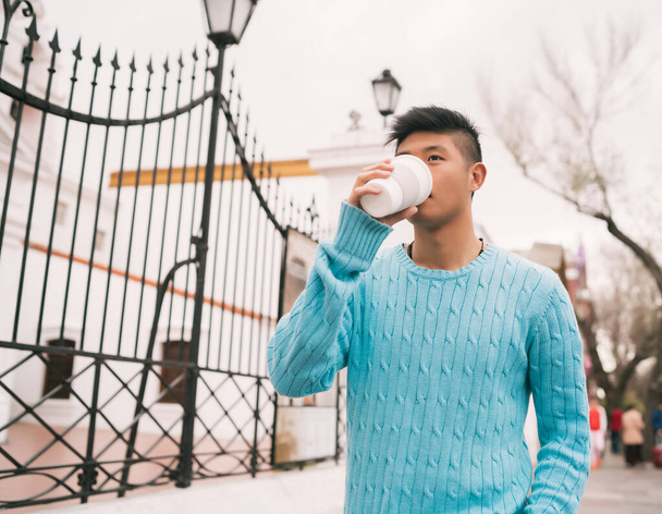 Asian man drinking a cup of coffee. - Фото, зображення