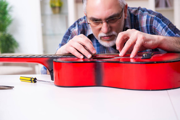 Senior male repairman repairing musical instruments at home - Fotoğraf, Görsel