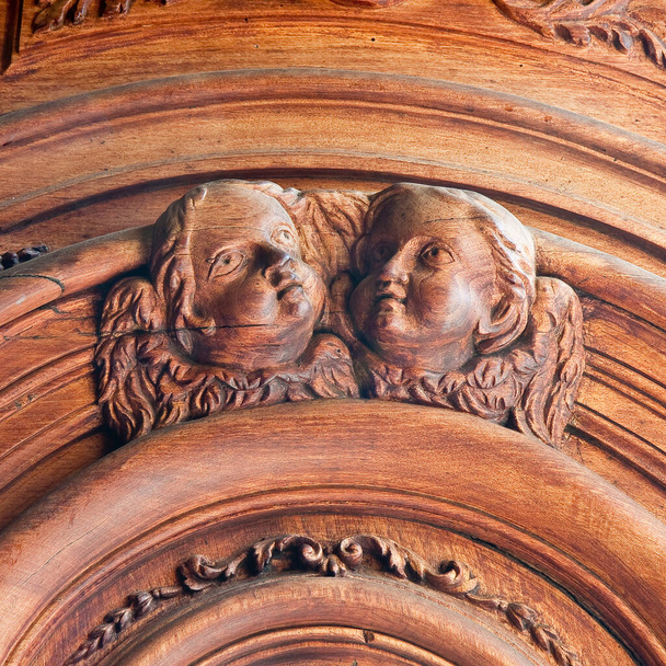 Escultura de un viejo ángel de madera contra una puerta de madera de una iglesia de más de 100 años. - Foto, imagen
