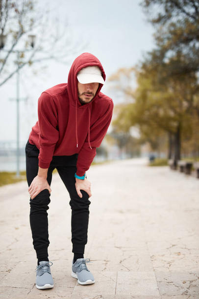 Athletic sporty man training in hoodie sweatshirt in urban city park. - Photo, Image
