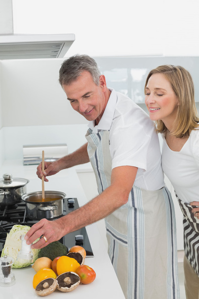 Side view of a couple preparing food in kitchen - Zdjęcie, obraz