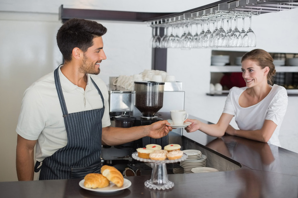 Friendly waiter giving coffee to a woman at coffee shop - Fotó, kép