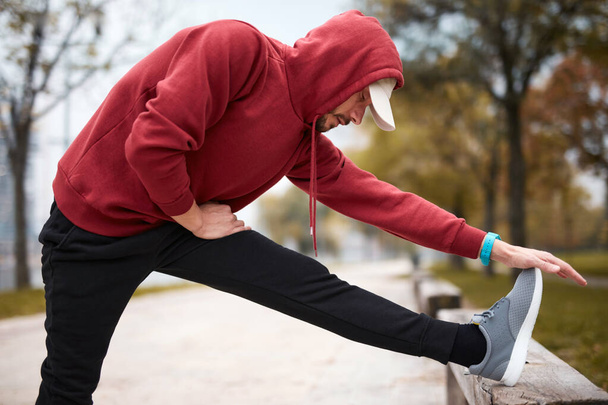 Athletic sporty man training in hoodie sweatshirt in urban city park. - Foto, Bild